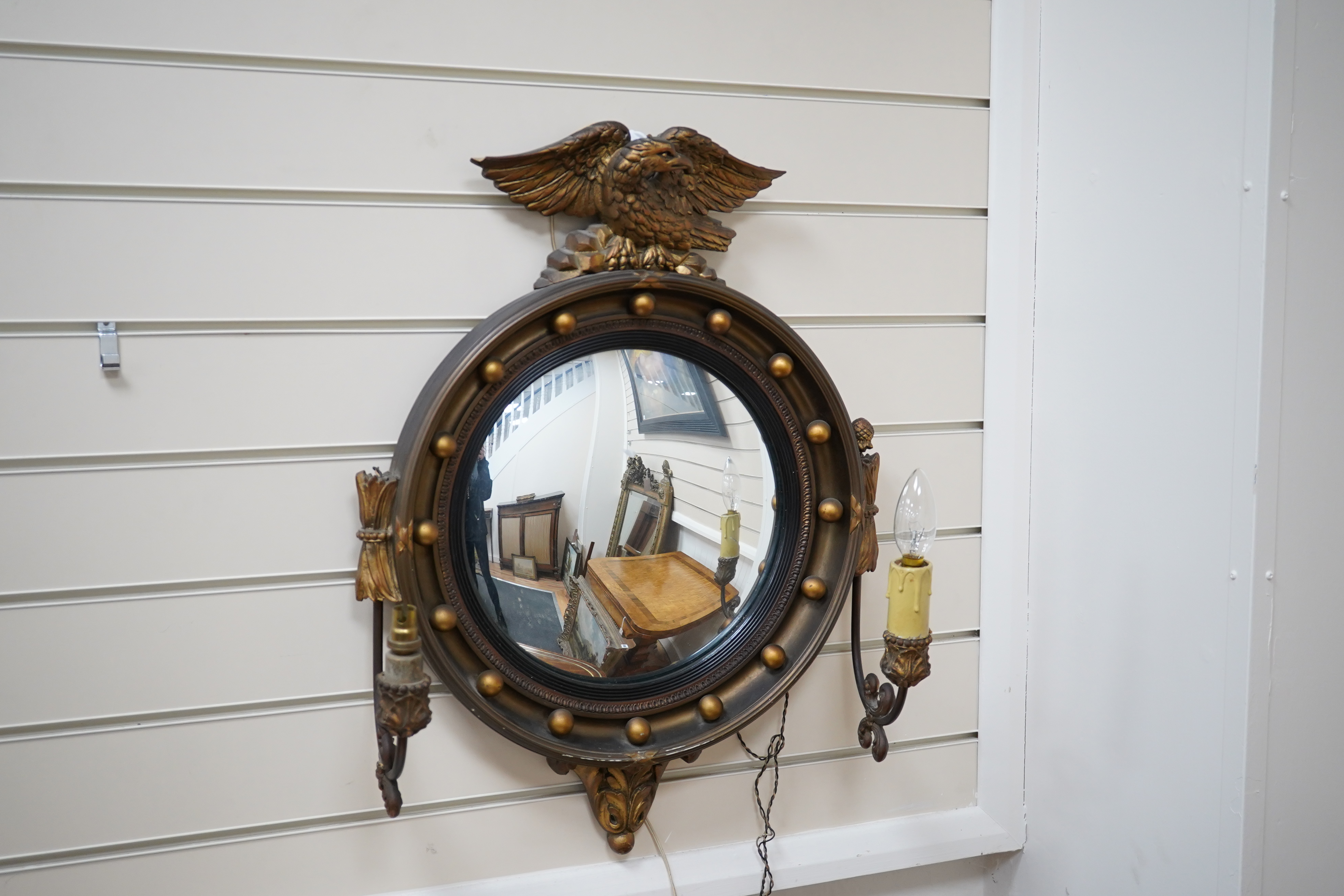 A circular convex gilt girandole mirror with carved eagle surmount, 62cm high. Condition - wing tip of eagle broken, gilt of frame scratched near the bottom, faux candle cover broken and the other missing